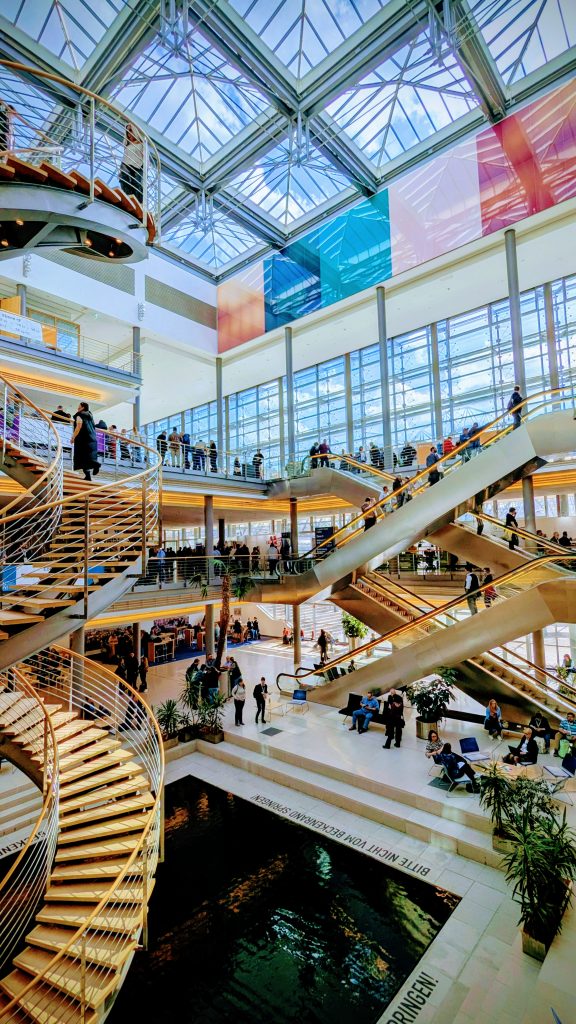 Das Treppenhaus im Congress Center Leipzig. Der Raum ist hoch und offen, viele Menschen sind im Bild.