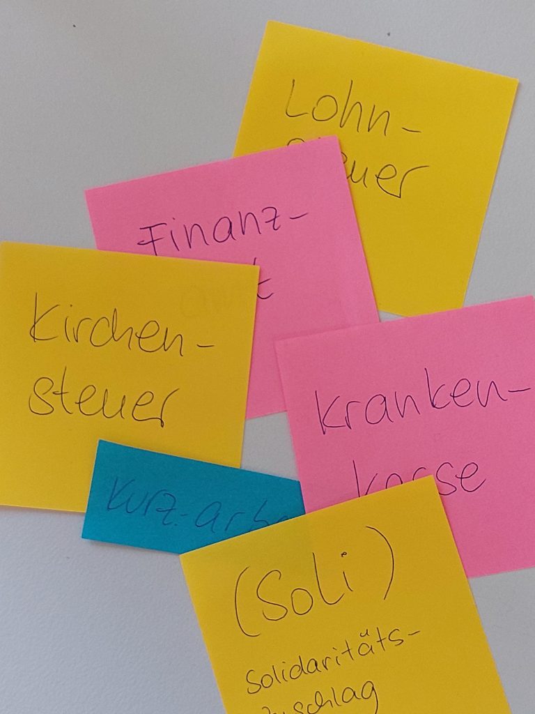 Bunte Post-Its mit Stichwörtern rund um Steuern und Sozialversicherungen.